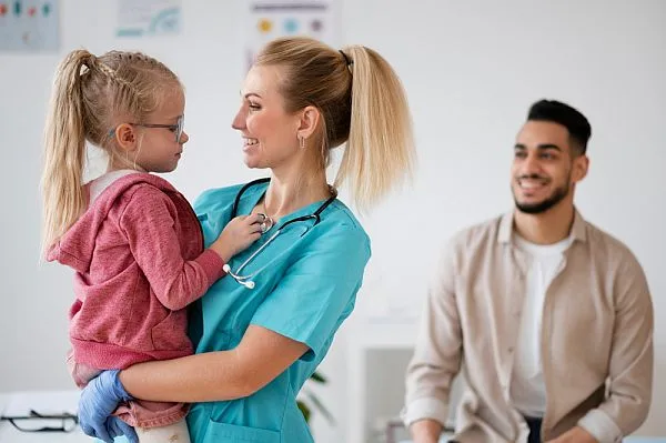 nurse holding child with parent watching