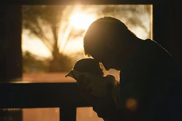 Man holding his baby head to head.